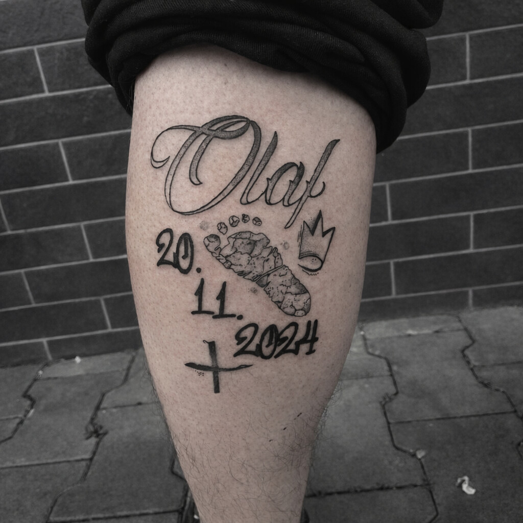 Minimalist realistic tattoo featuring a baby footprint with name and date, black ink linework tattoo