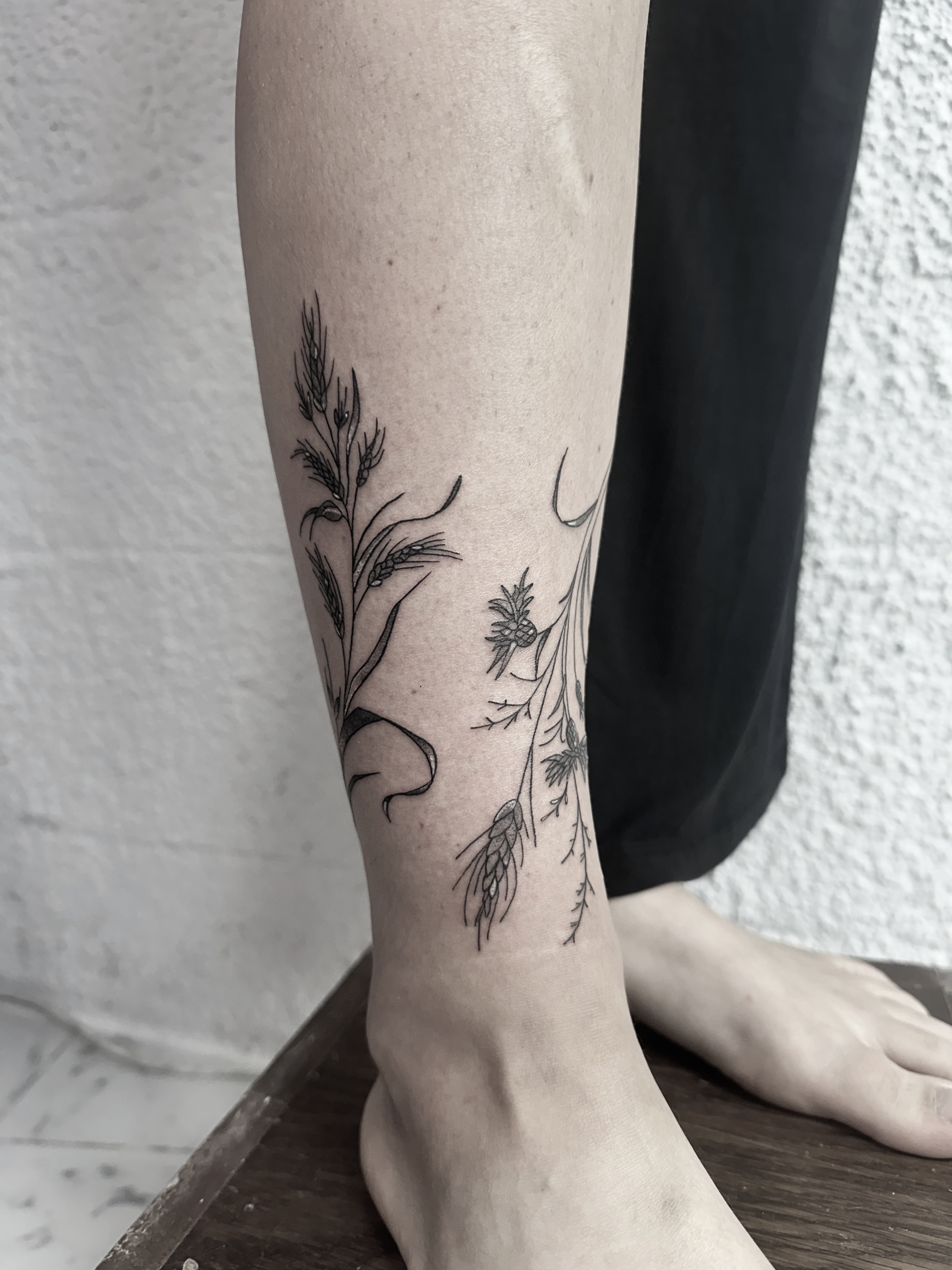 fine line botanical tattoo with wild grasses on the ankle