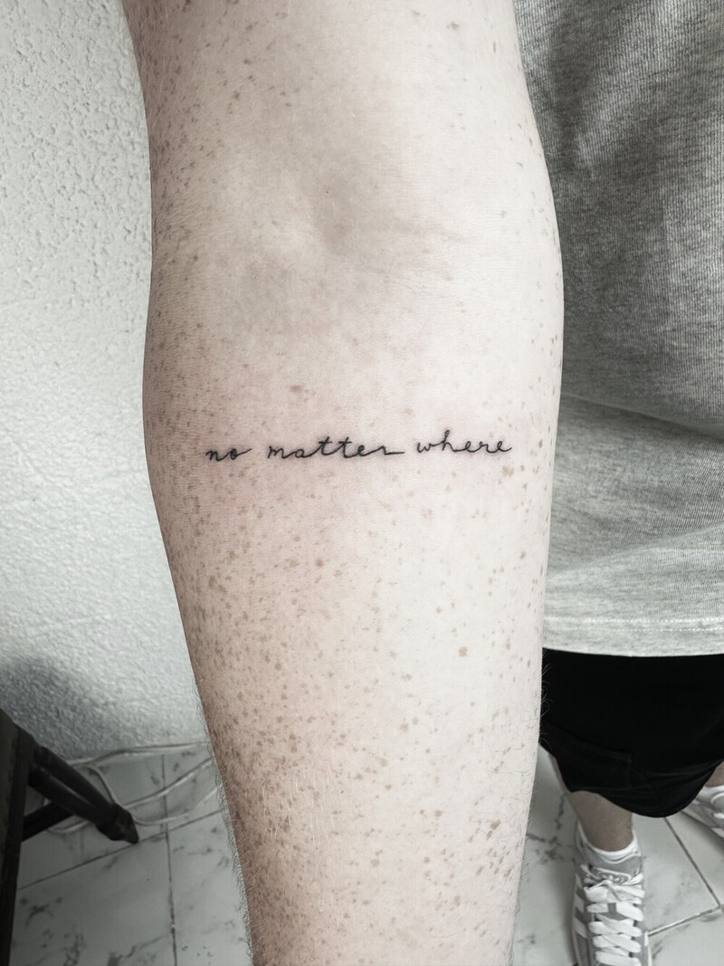 Minimalist script tattoo with text 'no matter where', fine line black ink lettering tattoo on inner forearm, delicate minimalist tattoo, professional tattoo photography