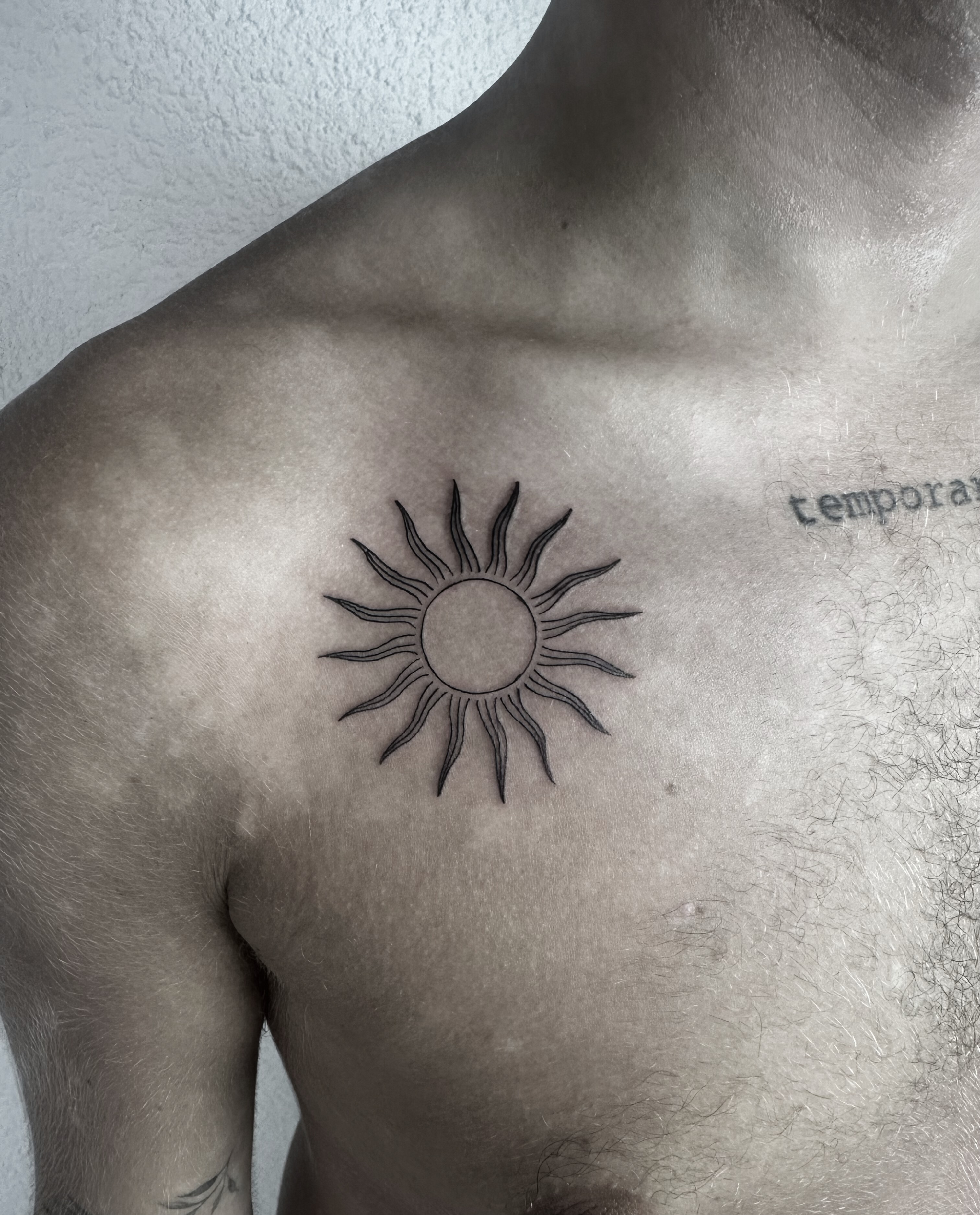 minimalist fine line sun tattoo on the chest